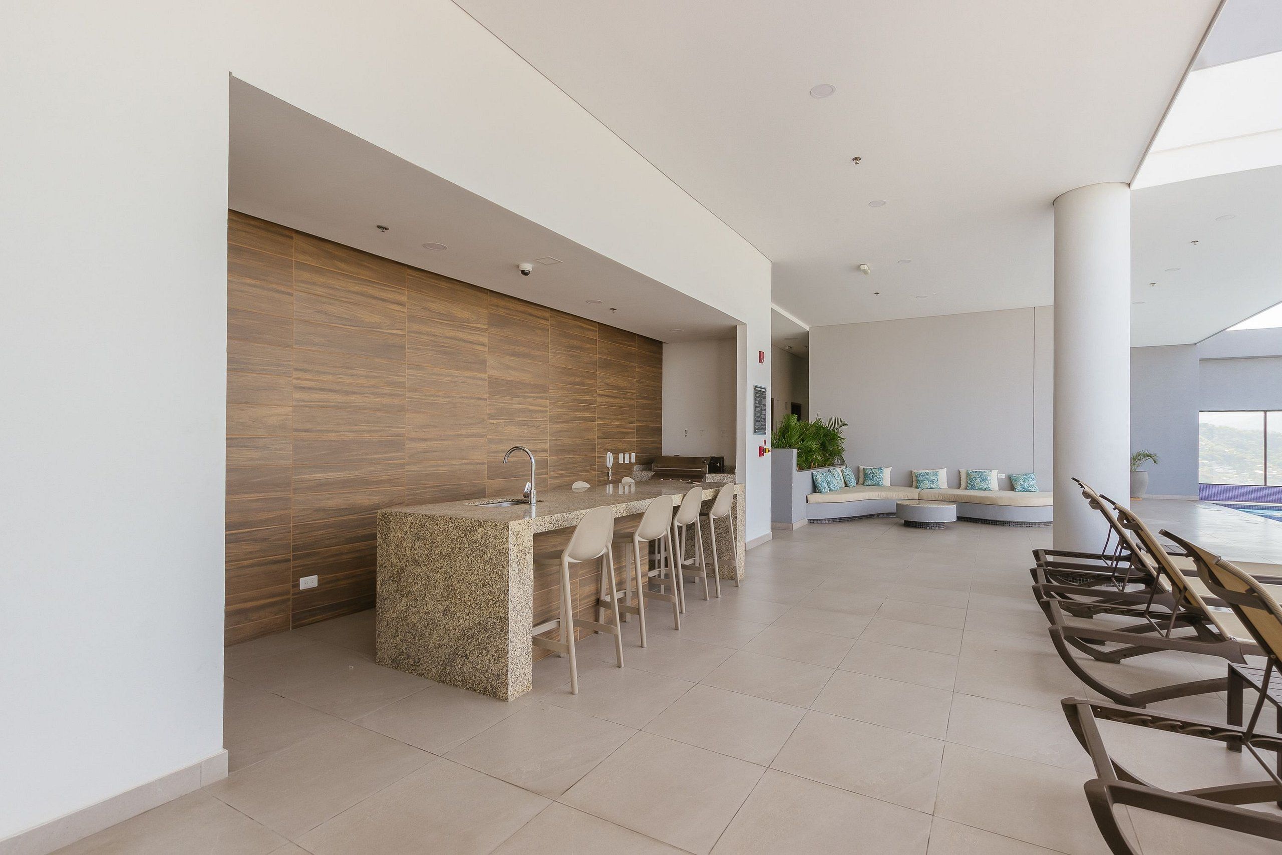 A modern kitchen with a granite island, bar stools, and a seating area with a sofa and chairs.