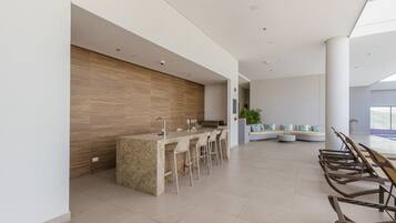 A modern kitchen with a granite island, bar stools, and a seating area with a sofa and chairs.