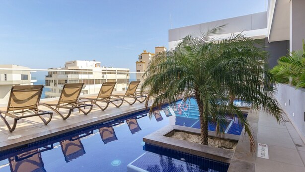 A rooftop pool with lounge chairs and a palm tree. - U-GO Edificio Ambar Roca en Rodadero Sur (Santa Marta)