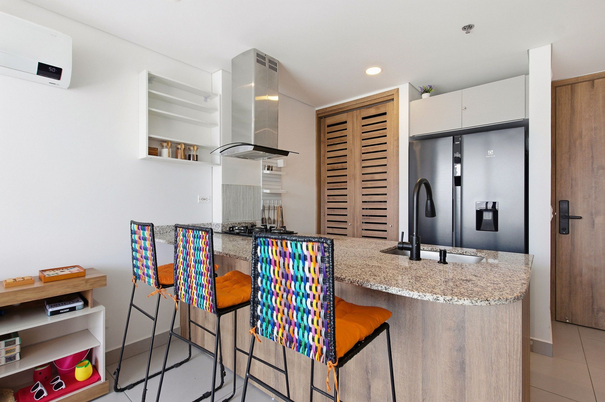A modern kitchen with a built-in island, stainless steel appliances, and a wooden door.