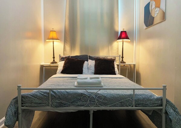 A neatly made bed with a patterned bedspread, two bedside lamps, and a framed picture on the wall.