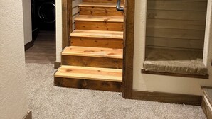 A wooden staircase with a handrail, carpeted steps, and a view into a laundry room. - Sturgis Cozy Cottage (Sturgis)