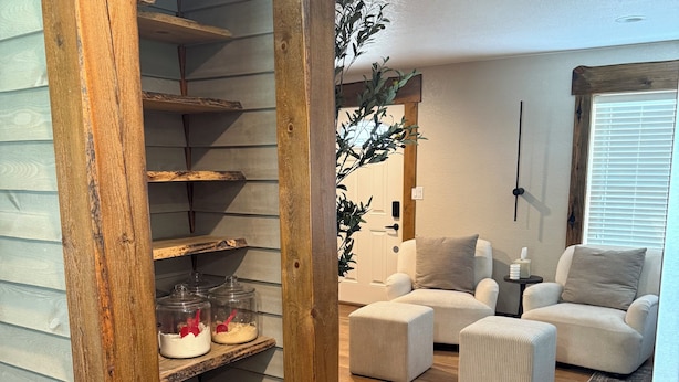 A cozy living room with a wooden staircase, a white sofa set, and a decorative plant. - Sturgis Cozy Cottage (Sturgis)