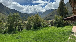A rural landscape with a wooden cabin, lush green fields, and mountains in the background. - 1BR Country Home w/ Garden & Mountain View (Taray)