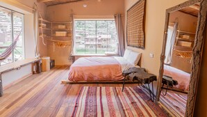 A bedroom with a wooden ceiling, a bed with a striped rug, a hammock, and a large window. - Bright Studio w/ Views, Top Wifi (Písac)