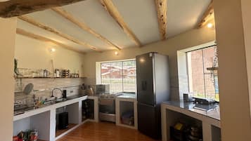 Una cocina con vigas de madera, un ventanal grande, un refrigerador y una estufa.
