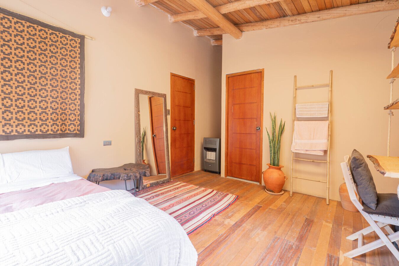 Una camera da letto con un letto, una scrivania, una sedia, una pianta e due porte.