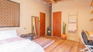 Una camera da letto con un letto, una scrivania, una sedia, una pianta e due porte.