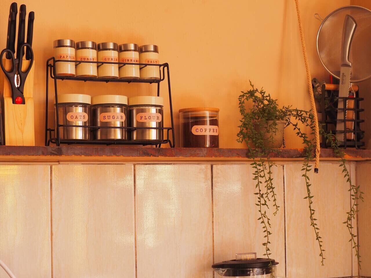 Een keukentop met potjes gevuld met ingrediënten zoals Paprika, Curry, Komijn, Kaneel, Zout, Havermout, Suiker, Bloem en Koffie.