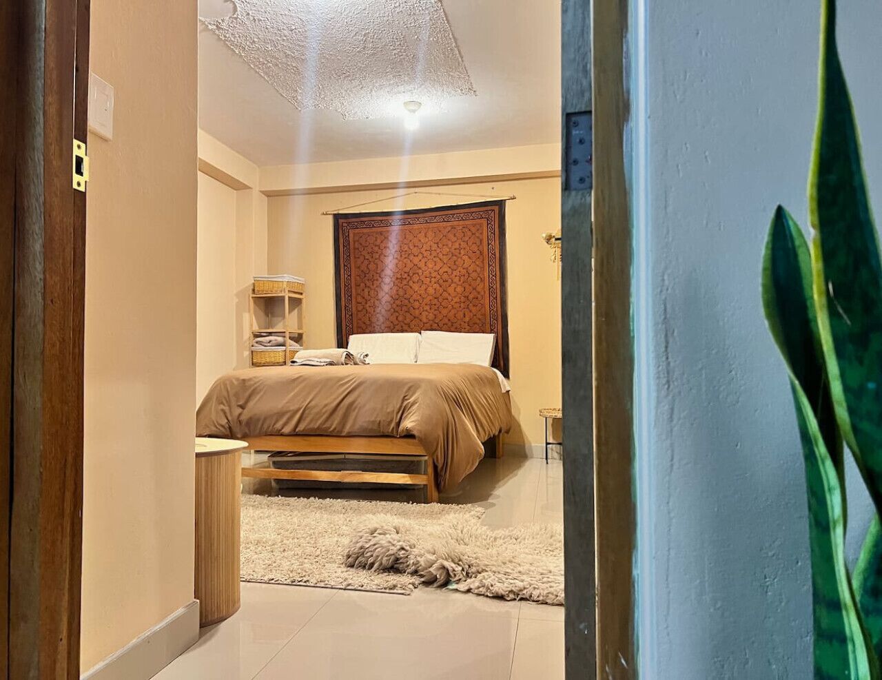 A bedroom with a bed, bedside table, and a large window.