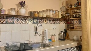 Una cocina con salpicadero de azulejos, un lavabo y diversos utensilios y recipientes.