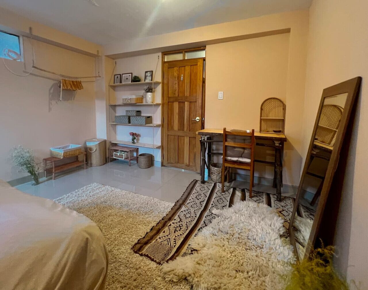 A cozy room with a bed, a desk, and a chair. There are shelves with items and a door leading to another room.