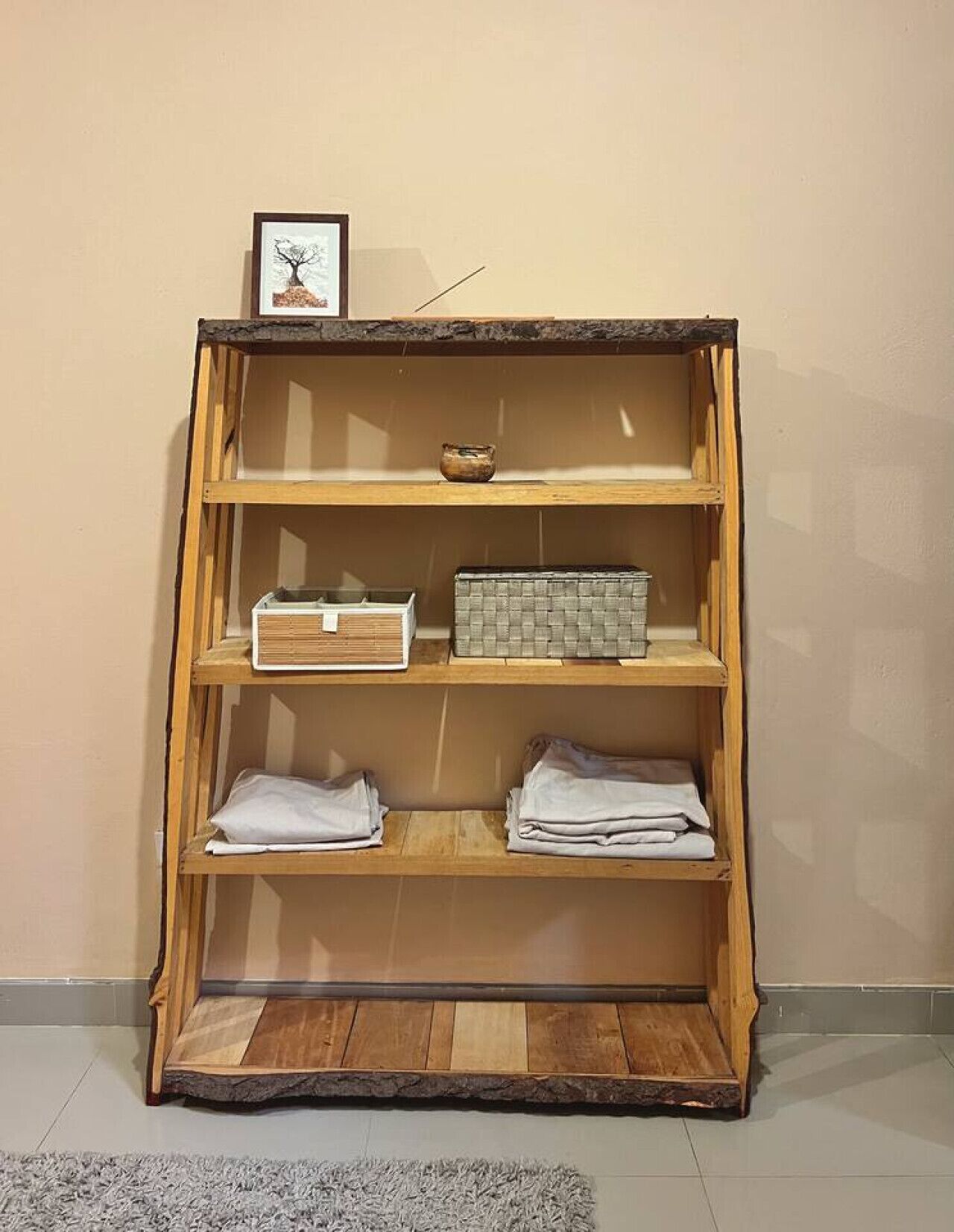 A wooden bookshelf with three shelves, each containing different items.