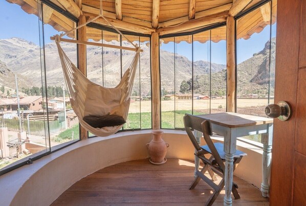 Una habitación con una hamaca, una mesa y vistas a las montañas.