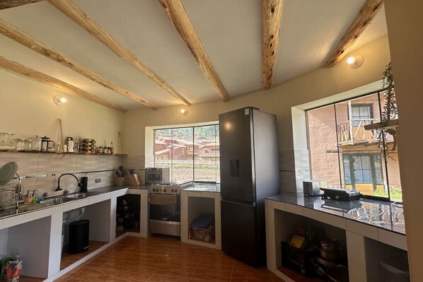 A modern kitchen with wooden beams, a large window, and a built-in oven. - Cosy Studio w/ Balcony, Hammock & Fast Wifi (Písac)