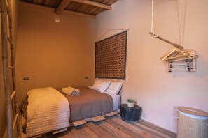 Una camera accogliente con un letto, una piccola pianta e un appendiabiti.