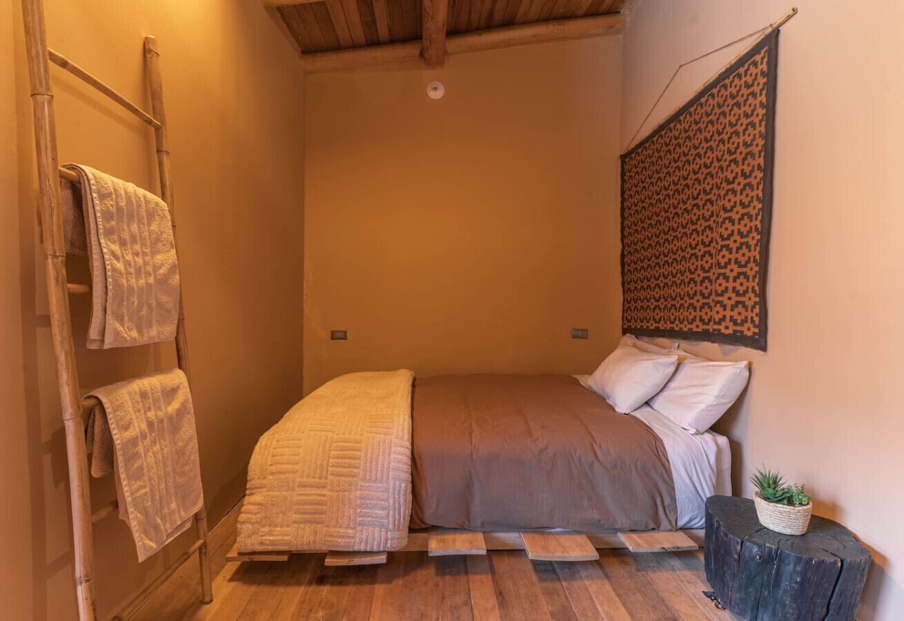 Ein kleines, gemütliches Schlafzimmer mit Bett, einer Leiter und einer dekorativen Wandverkleidung.