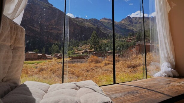 Une pièce dotée d’une grande fenêtre donnant sur un paysage de montagnes et une vallée.