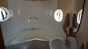 Une salle de bain avec une baignoire, un lavabo et deux miroirs.