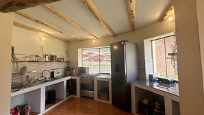 Une cuisine avec des poutres en bois, une grande fenêtre, un réfrigérateur et une cuisinière.