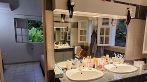 Een badkamer met twee wasbakken, een grote spiegel en een raam.