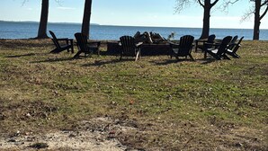 A beach with several Adirondack chairs arranged in a semi-circle facing the water. - Coles Point Marina (Hague)