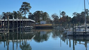 A marina with docked boats, a covered structure, and a small building in the background. - Coles Point Marina (Hague)