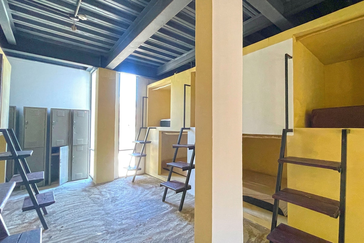 A room with lockers, a ladder, and a yellow wall.