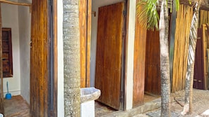 A traditional wooden structure with a door and a stone basin, likely a bathroom or wash area. - Mr Zamna Tulum (Tulum)