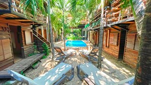 A pool area with wooden deck chairs, a small pool, and a staircase leading to a wooden building. - Mr Zamna Tulum (Tulum)