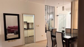 Una sala de estar moderna con comedor, una cocina al fondo y un espejo grande en la pared.