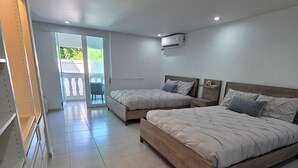 Een slaapkamer met twee bedden, een schuifdeur naar een balkon en een witte kledingkast.