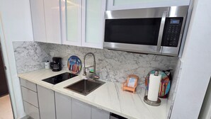 Een moderne keuken met witte kasten, een roestvrijstalen magnetron, een spoelbak en een vaatwasser.