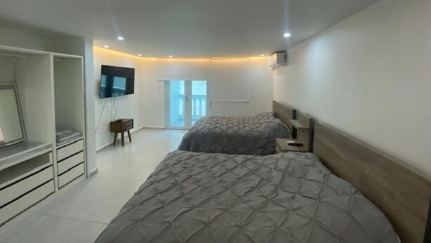 Een slaapkamer met een bed, een televisie, een kledingkast en een schuifdeur naar een balkon.