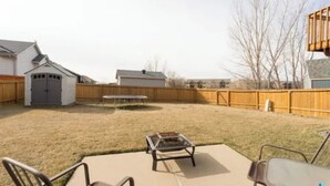 A backyard with a patio area, a small shed, and a wooden fence. - Charming 2-bedroom bed & breakfast in serene Sioux Falls (Sioux Falls)