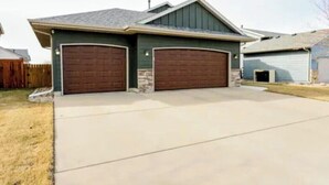 A two-car garage attached to a house with a sloped roof and a stone foundation. - Charming 2-bedroom bed & breakfast in serene Sioux Falls (Sioux Falls)
