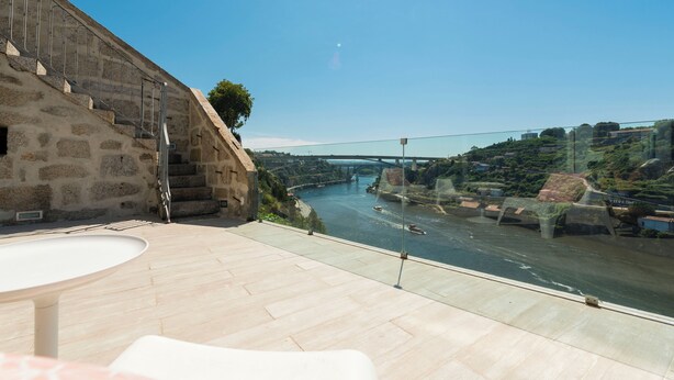 A terrace with a view of a river and a bridge.