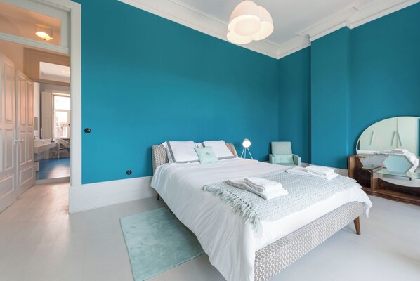 A bedroom with a large bed, a bedside table, a chair, and a mirror. - Miradouro - Townhouse with a breathtaking view (Porto)