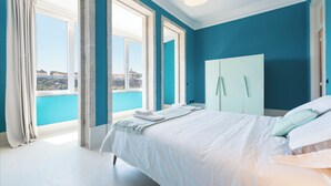 A bedroom with a large bed, a wardrobe, and a view of the city.