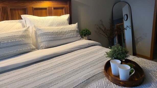 A neatly made bed with pillows and a tray of mugs, a small potted plant, and a wall-mounted mirror. - Timberline Retreat - Sleeps 9, large backyard, well stocked kitchen! (Windsor)