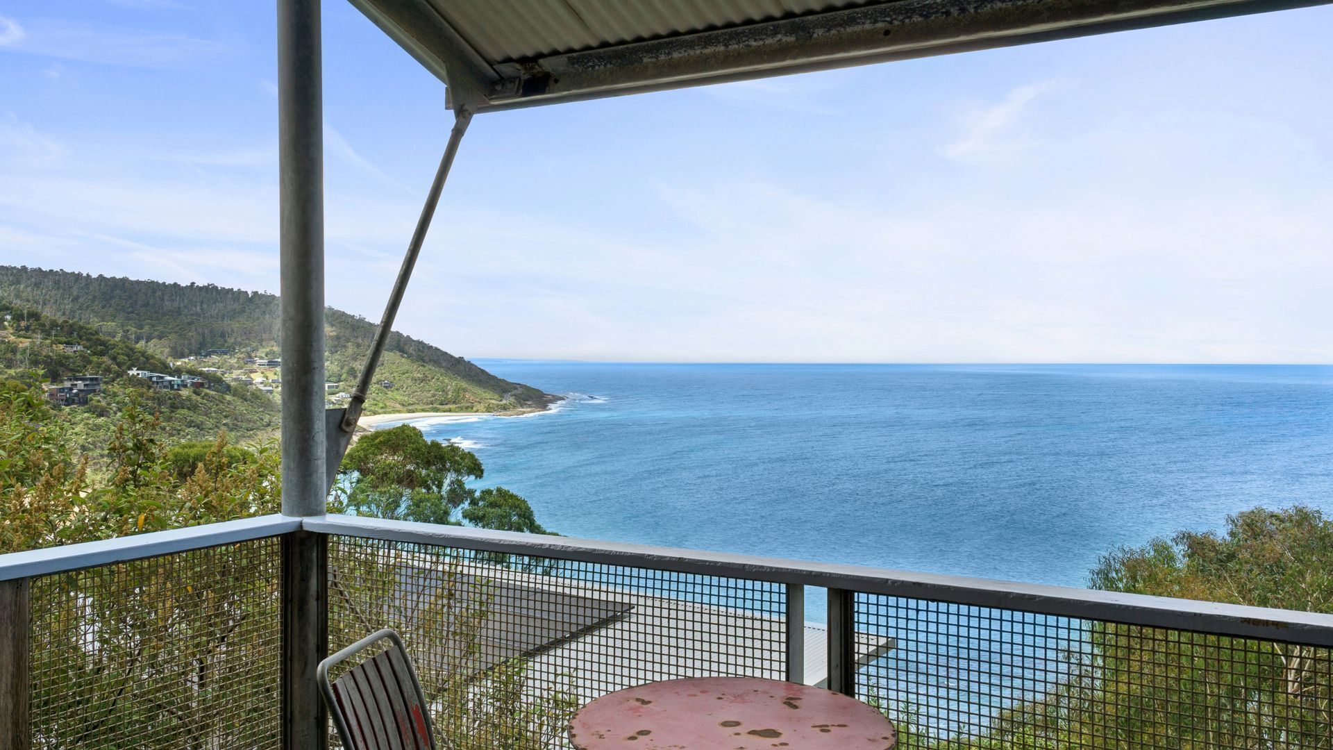 Ein Balkon mit Blick auf das Meer und eine hügelige Landschaft.