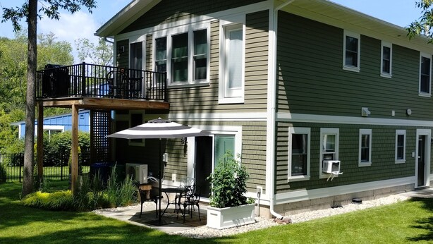 Une maison à deux étages dotée d’un balcon, d’une terrasse couverte et d’une pelouse bien entretenue.