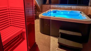 Un bain à remous dans une pièce aux murs lambrissés et séparée par une cloison en verre.