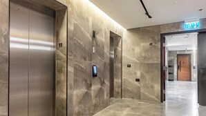 A modern hallway with marble walls and a polished floor, featuring three elevators and a visible door number 11. - MR Savyon view 2BR with 2 balcony 77 (Jerusalem)