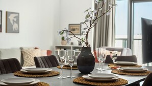 A dining table set with plates, glasses, and a vase with flowers. - MR Savyon view 2BR with 2 balcony 77 (Jerusalem)