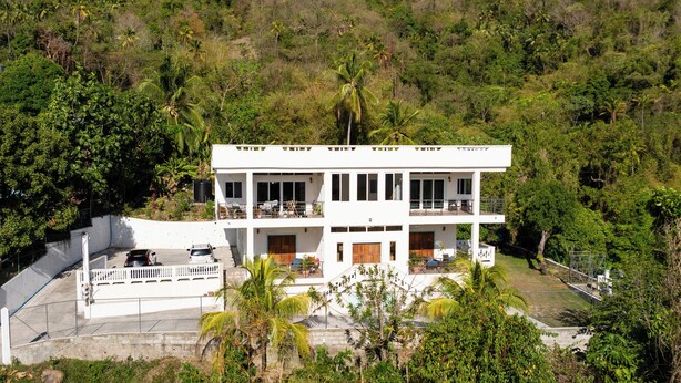 Un edificio de dos pisos con fachada blanca, múltiples ventanas y balcones.