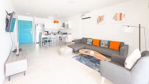 A modern living room with a grey sofa, a coffee table, and a TV mounted on the wall. - Seashell Sanctuary -S2-107- 2 bed, 2 bath (Punta Chame)