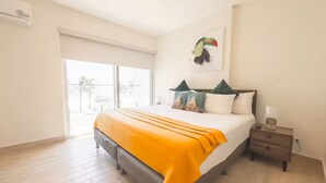A bedroom with a bed, a nightstand, a window, and a door. - Seashell Sanctuary -S2-107- 2 bed, 2 bath (Punta Chame)