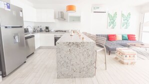 Eine moderne Küche mit einer Granitinsel, Edelstahlgeräten und einem grauen Sofa mit bunten Kissen.