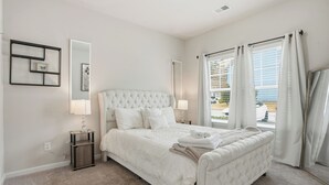 Un dormitorio con una cama grande, dos mesitas de noche, un espejo y vistas al exterior.
